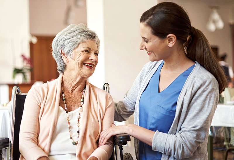 Elderly woman and nurse talk in a skilled nursing facility dining room at Alpine Skilled Nursing & Rehabilitation in Ruston, LA