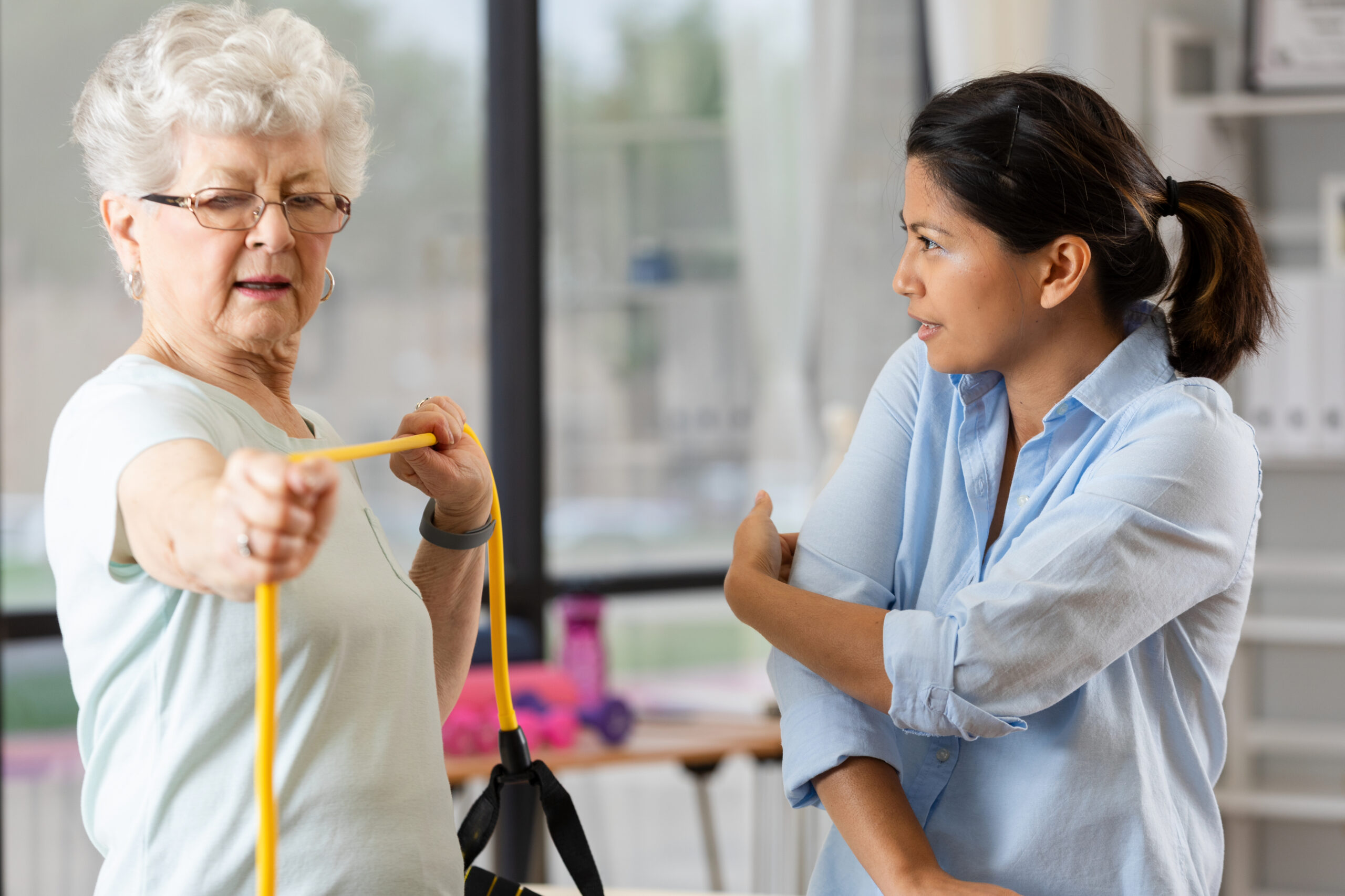 Physical therapist assists senior woman with resistance band exercise for post operative orthopedic care at Alpine Skilled Nursing & Rehabilitation in Ruston